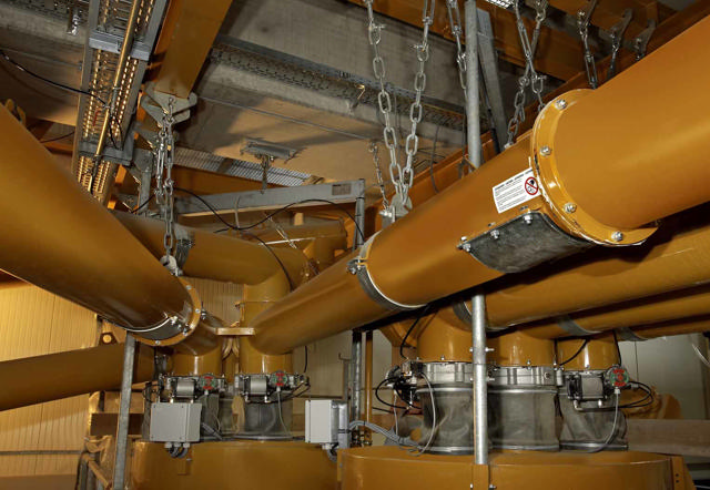 Yellow screw conveyors shown in a production hall.