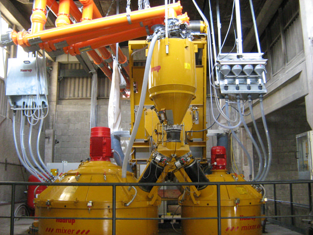 Admixture weigh hopper supplying two yellow concrete mixers.