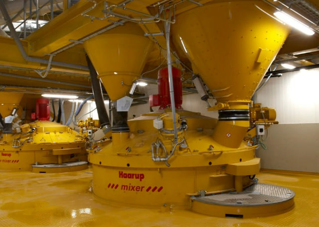 Two yellow concrete mixers in a production building with a beautiful, yellow floor.