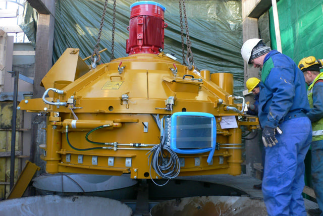 New yellow concrete mixer being installed at a production site.